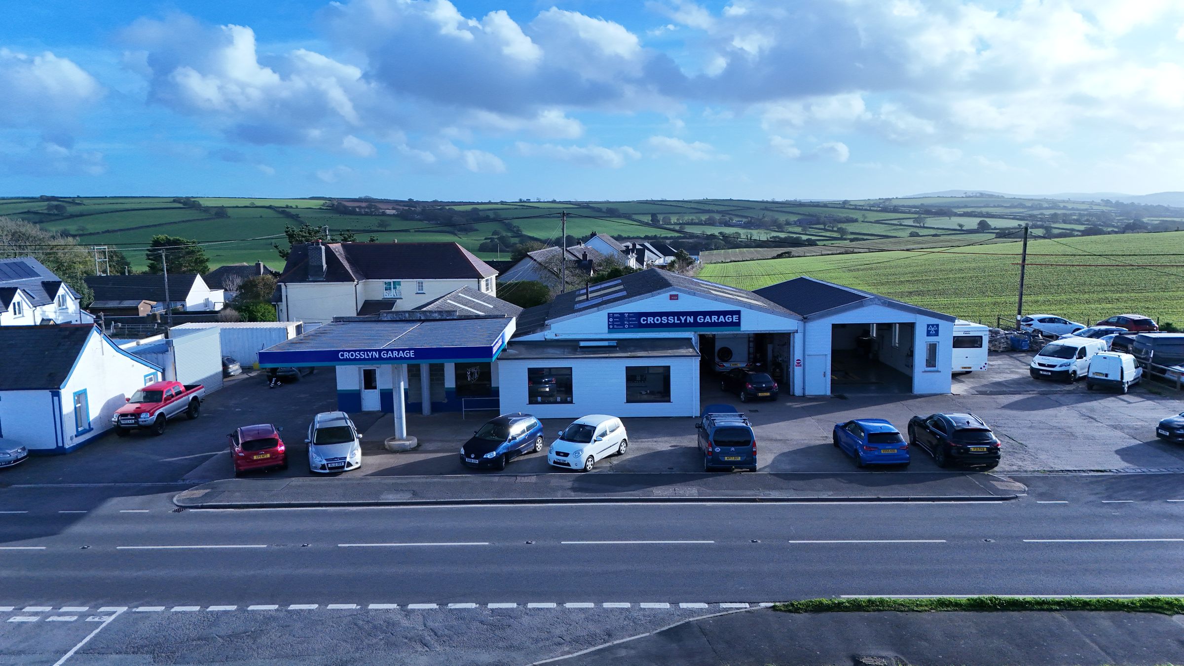 Crosslyn Garage from the air: the workshop and its MOT bays beside the A487 at Blaenannerch, with green fields behind